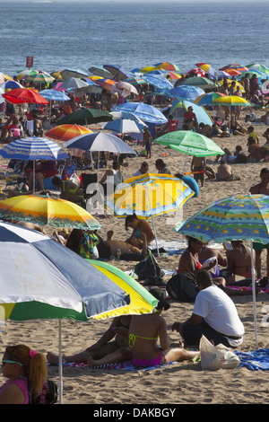 People fill the beach with colorful beach umbrellas on a hot summer day at Coney Island, Brooklyn, NY. Stock Photo
