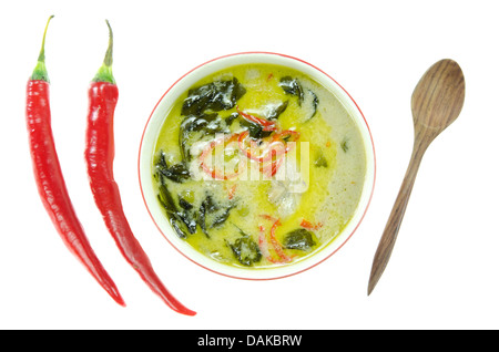 top view green chicken curry in bowl and red chili , wooden spoon over white background Stock Photo