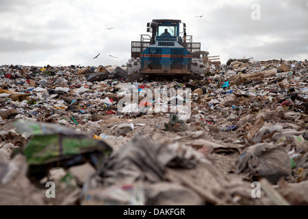 Garbage piles up in landfill site each day while truck covers it with sand for sanitary purpose Stock Photo