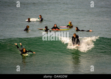 Teen boy and girl members of the San Clemente, CA, High School surfing team practice in wetsuits in the cold Pacific water. Stock Photo