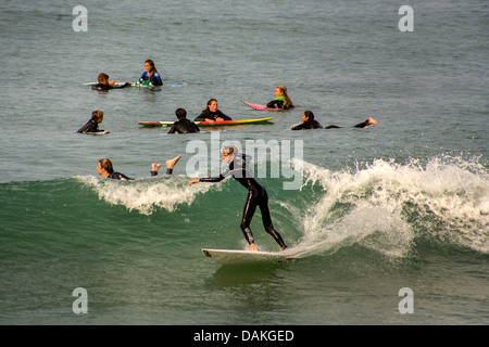 Teen boy and girl members of the San Clemente, CA, High School surfing team practice in wetsuits in the cold Pacific water. Stock Photo