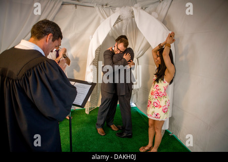 A Deputy Commissioner of Civil Marriages in West Hollywood, CA, officiates at a civil marriage ceremony for a gay male couple. Stock Photo