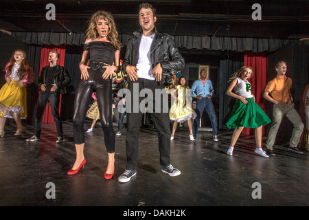 In 1950's clothing, Sandy Dumbrowski (left) and Danny Zuko lead the cast in ensemble number of a student production of 'Grease'. Stock Photo