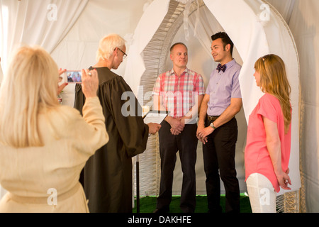 A Deputy Commissioner of Civil Marriages in West Hollywood, CA, officiates at a civil marriage ceremony for a gay male couple. Stock Photo