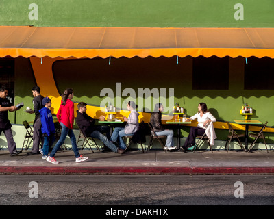 Diners eat lunch at a sidewalk cafe in Los Angeles. Note server at far left with bill. Stock Photo