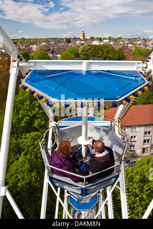 family with one child in a gondola of ferris wheel with outlook to the townhall tower, Germany, North Rhine-Westphalia, Ruhr Area, Witten Stock Photo