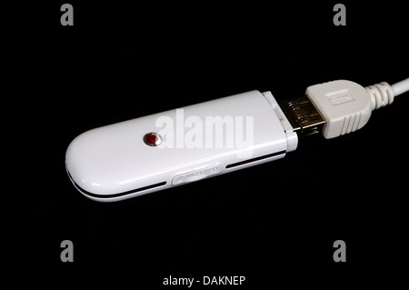 Broadband dongle with USB connector and Micro SD slot against a black background. Stock Photo