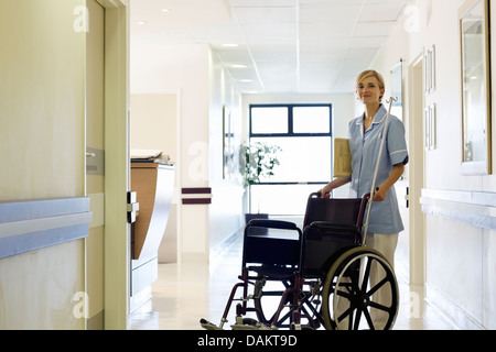 Nurse pushing wheelchair in hospital hallway Stock Photo