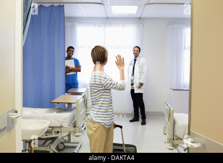 Patient waving to doctor in hospital room Stock Photo