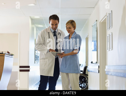 Doctor and nurse using tablet computer in hospital hallway Stock Photo