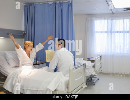 Doctor talking to cheering patient in hospital room Stock Photo