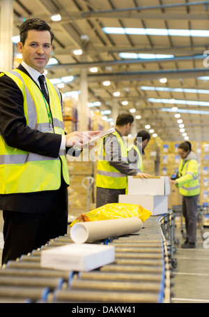 Workers checking packages on conveyor belt in warehouse Stock Photo