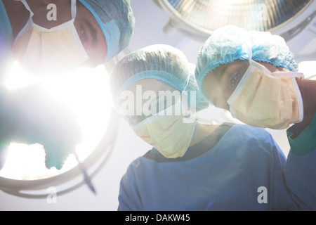 Surgeons bent over patient in operating room Stock Photo