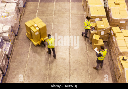 Workers carting boxes in warehouse Stock Photo - Alamy