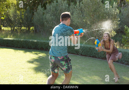 Couple playing with water guns in backyard Stock Photo