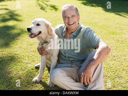 Older man hugging dog in backyard Stock Photo
