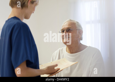 Nurse talking to older patient in hospital room Stock Photo