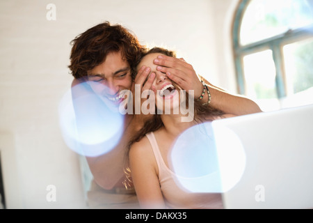 Man covering girlfriend's eyes indoors Stock Photo