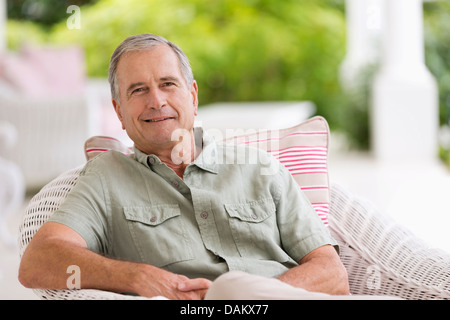 Older man sitting in armchair outdoors Stock Photo
