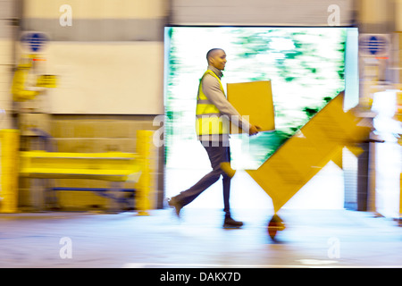 Blurred view of workers carrying boxes in warehouse Stock Photo