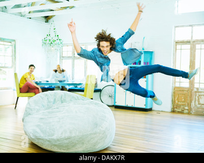 Man jumping into beanbag chair Stock Photo
