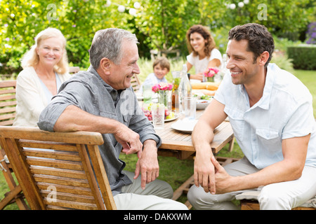 Family sitting at table outdoors Stock Photo