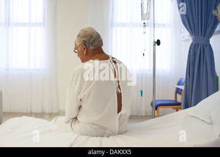 Older patient wearing gown in hospital room Stock Photo