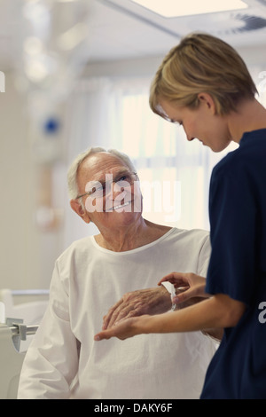 Nurse reading older patient's medical bracelet in hospital Stock Photo
