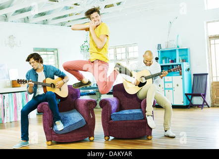 Men playing music together in living room Stock Photo