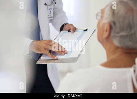 Doctor showing medical chart to patient in hospital room Stock Photo