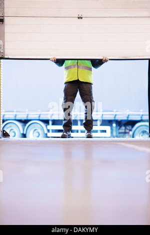 Worker lifting door in warehouse Stock Photo