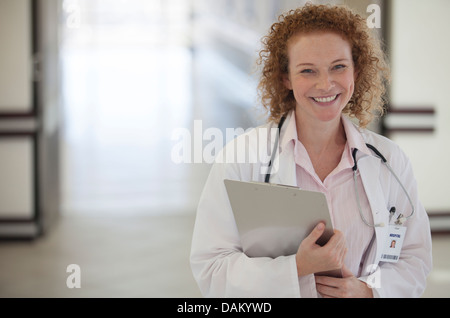 Doctor carrying clipboard in hospital hallway Stock Photo