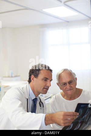 Doctor showing x-rays to older patient in hospital room Stock Photo