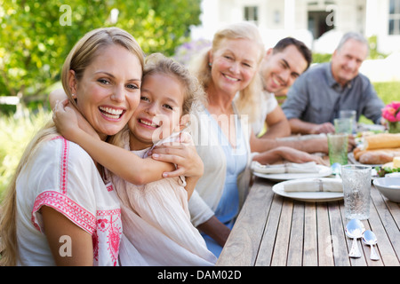 Mother and daughter hugging at table outdoors Stock Photo