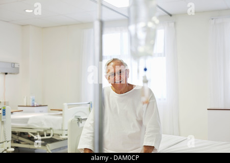 Older patient sitting on bed in hospital room Stock Photo
