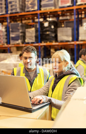 Workers using laptop in warehouse Stock Photo