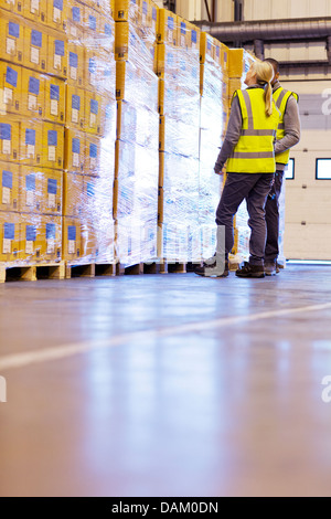 Workers examining stacks of boxes in warehouse Stock Photo