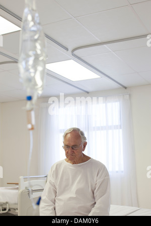 Older patient sitting on bed in hospital room Stock Photo