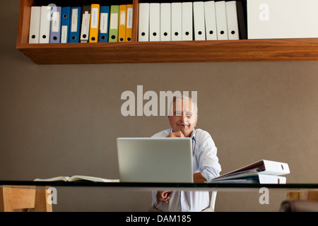 Older man sitting at desk Stock Photo