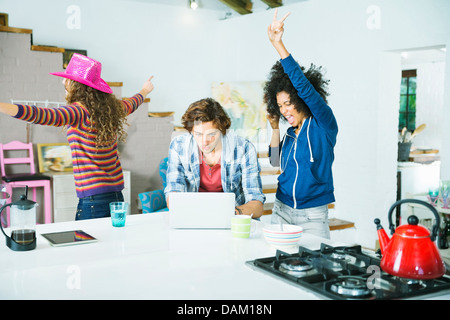 Women dancing around man in kitchen Stock Photo