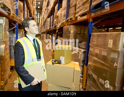 Businessman holding clipboard in warehouse Stock Photo
