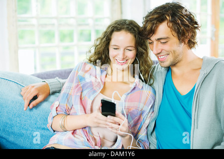 Couple listening to earphones together on sofa Stock Photo