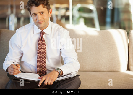 Businessman making notes on sofa Stock Photo