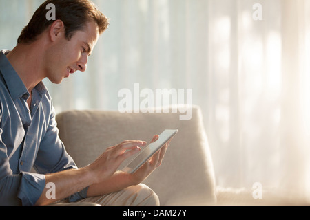 Man using tablet computer on sofa Stock Photo