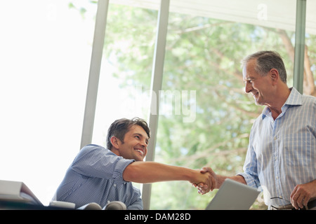 Men shaking hands in living room Stock Photo