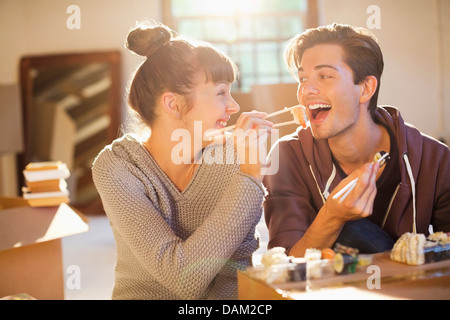 Couple eating sushi together in new home Stock Photo