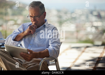 Older man using tablet computer outdoors Stock Photo