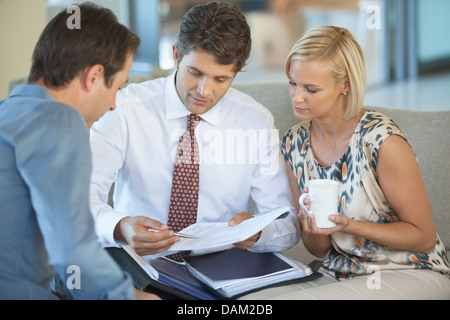 Financial advisor talking to couple on sofa Stock Photo