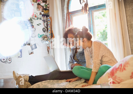 Women using laptop together in bedroom Stock Photo