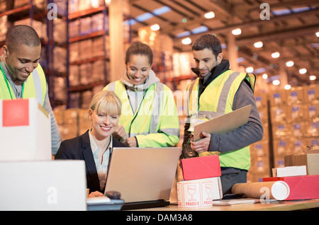 Businesswoman and workers using laptop in warehouse Stock Photo
